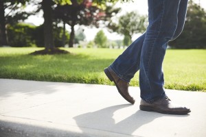 a man from the legs down wearing jeans and walking in a park