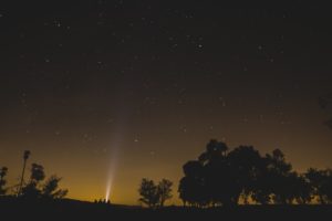 A flashlight beam shining into the sky on a dark night. 