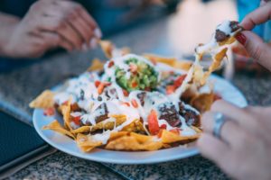 Two people sharing a plate of nachos.