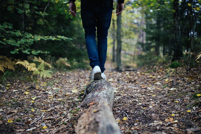 woman walking on a log through the woods