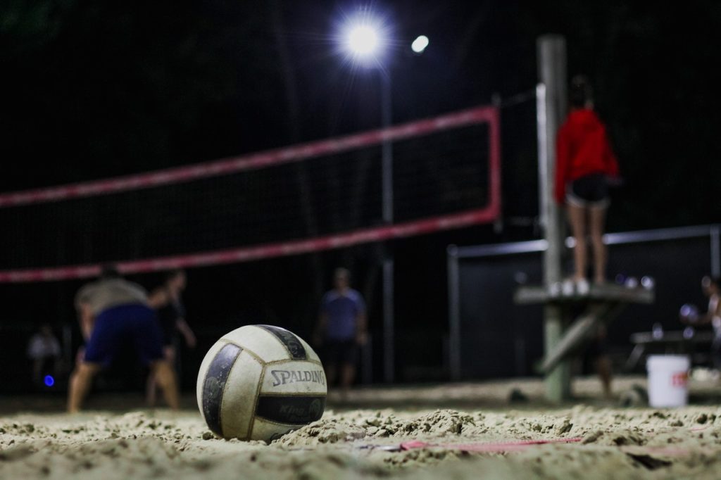 A volleyball sits on the sand volleyball courts in Country Club Village